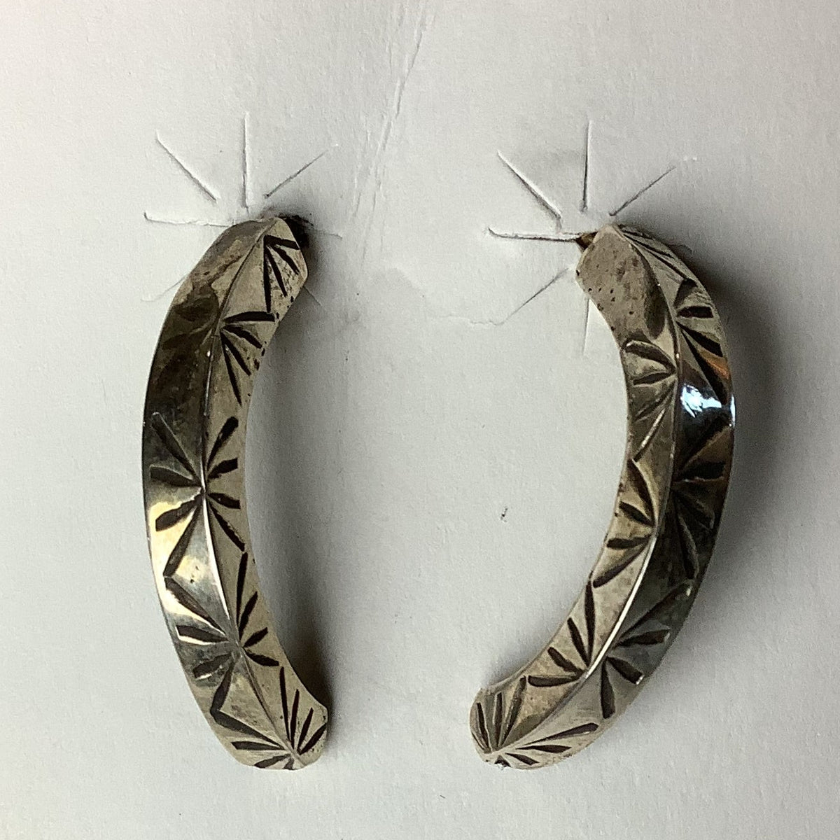 Sterling silver patterned post earrings with a traditional Native three point marking, displayed on a grey background.