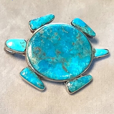 Turquoise turtle pendant on a beige fabric background